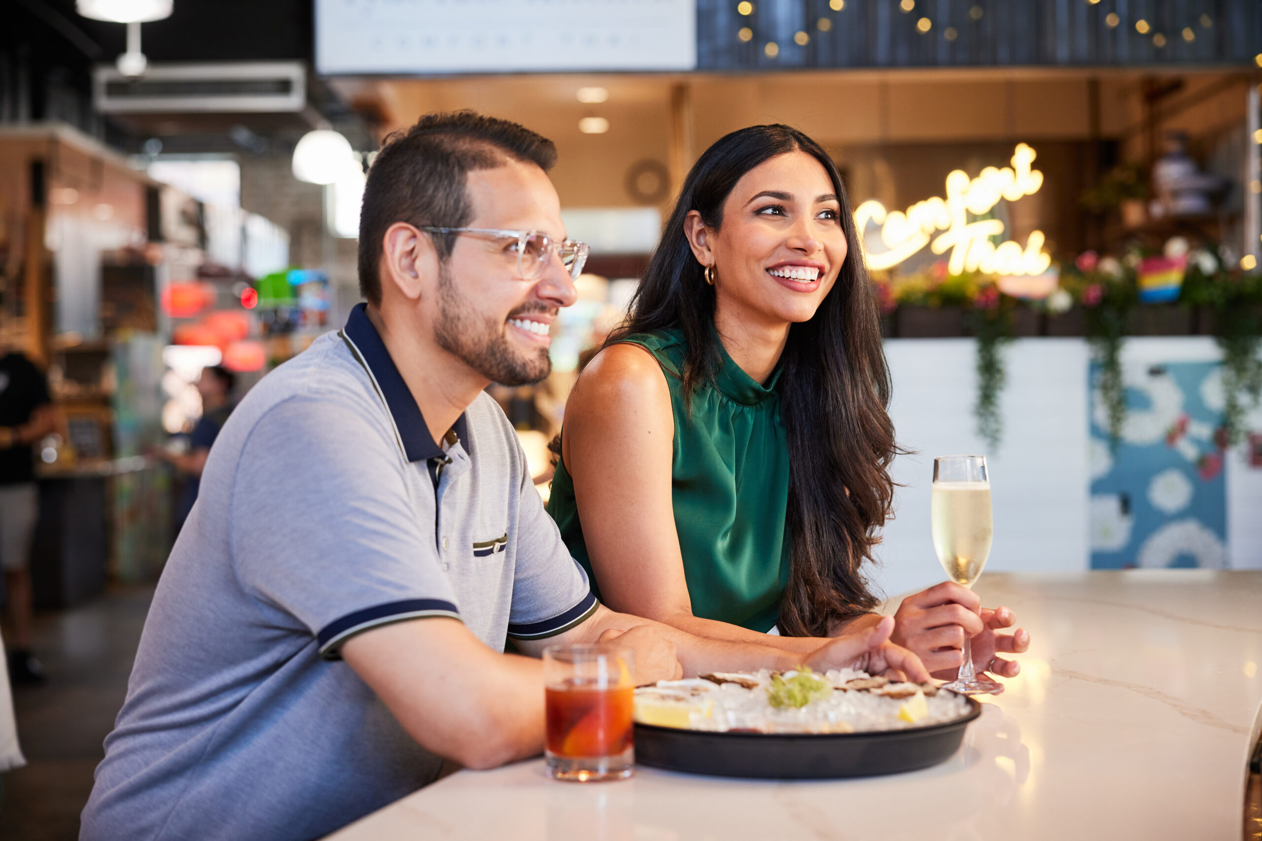 Man and woman sitting at food hall counter with oysters