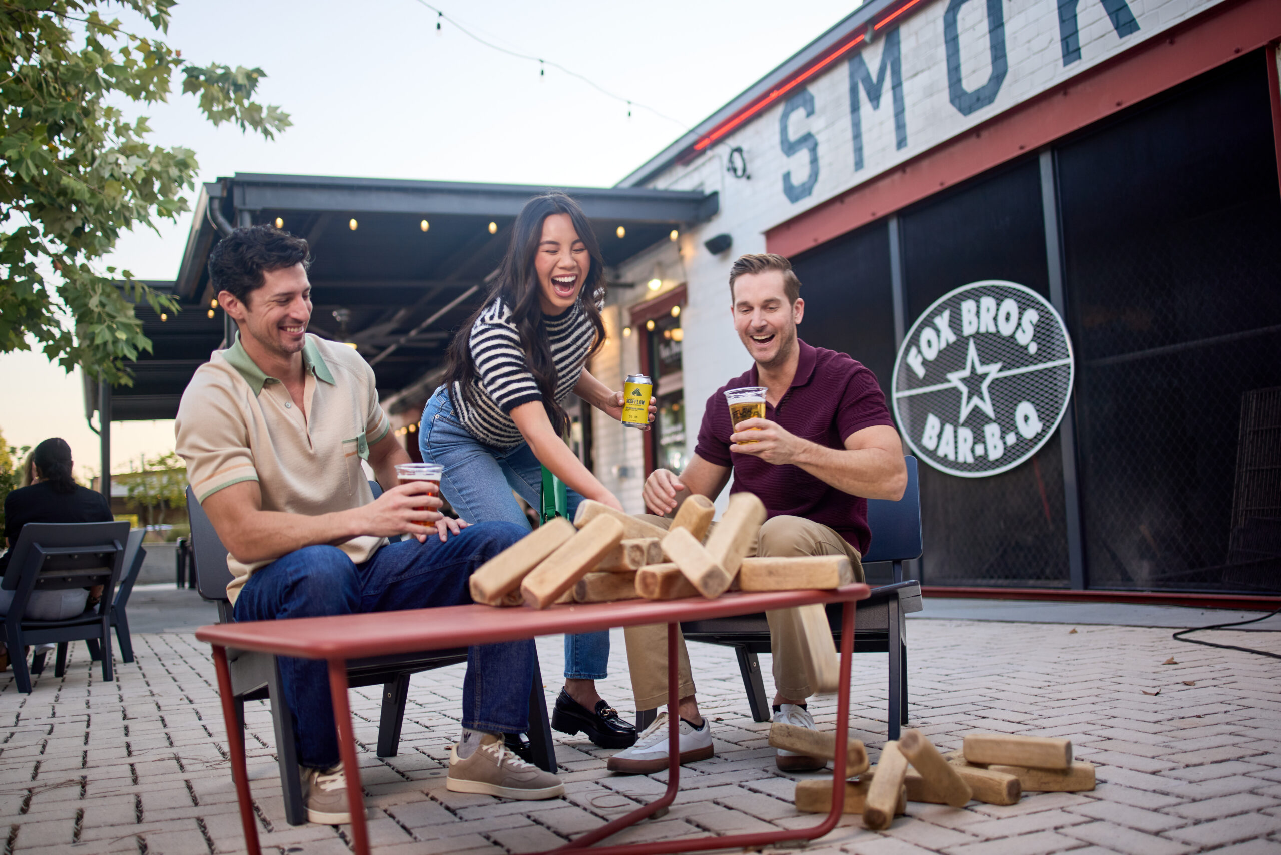 Group of two men and one woman playing jenga outside Fox Bros Bar-B-Q