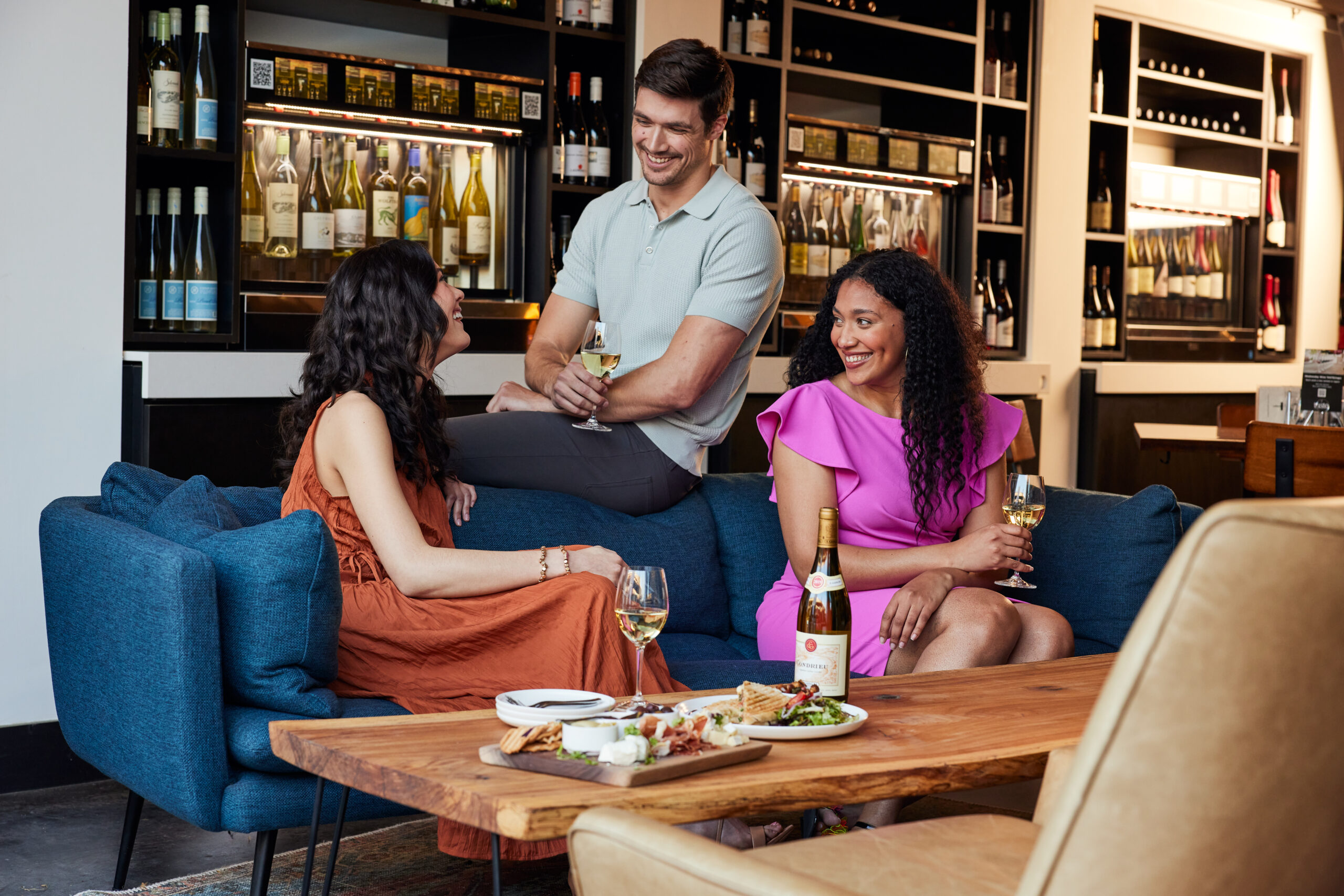 Group of two women and one man sitting on a couch inside a wine bar