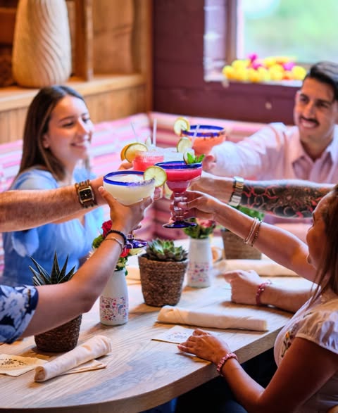 Group sitting at table cheersing with margaritas
